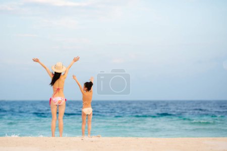 Téléchargez les photos : Mère et fille étendant leurs mains sur la plage - en image libre de droit