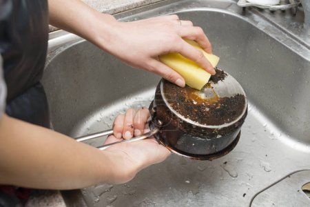 Woman's hands to polish burned pot