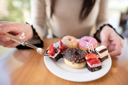 Foto de Una mujer que come un montón de dulces - Imagen libre de derechos