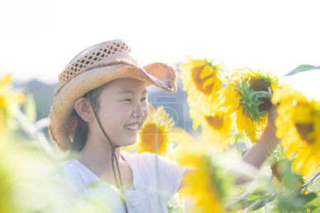 Téléchargez les photos : Mignonne asiatique fille posant dans tournesol champ - en image libre de droit