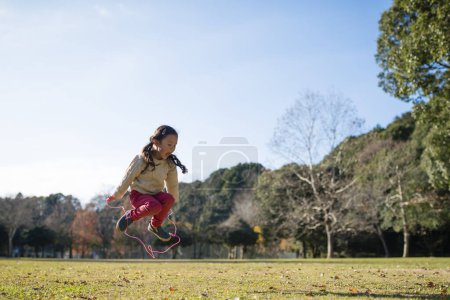 Téléchargez les photos : Petite fille avec corde à sauter dans le parc. - en image libre de droit
