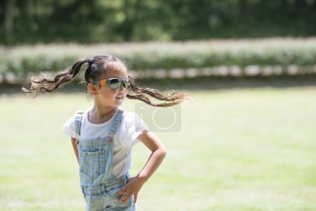 Téléchargez les photos : Fille avec des lunettes de soleil sur herbe verte dans le parc - en image libre de droit