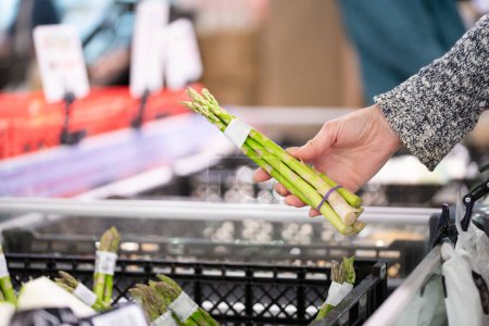 Woman's hand choosing asparagus at the supermarket