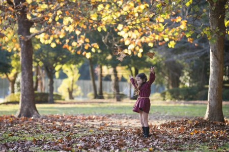 Photo for Girl playing with fallen leaves - Royalty Free Image