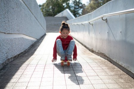 Téléchargez les photos : Belle petite fille asiatique sur skateboard dans parc - en image libre de droit
