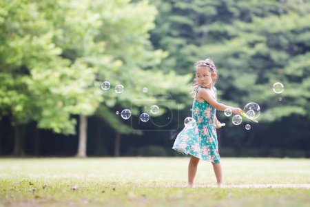 Happy little girl playing with soap bubbles
