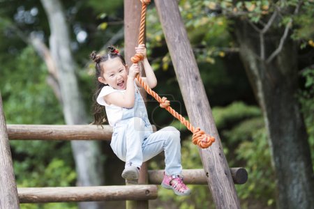 Téléchargez les photos : Petite fille grimpant sur une corde dans le parc - en image libre de droit