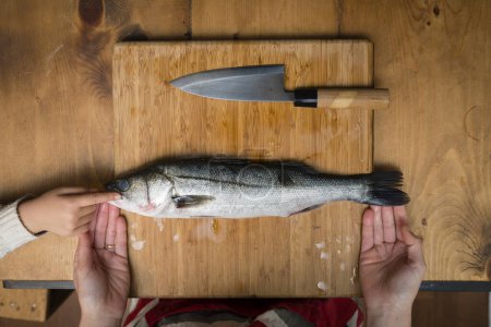 Photo for Sea bass cooking on wooden board - Royalty Free Image