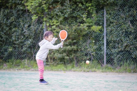 Téléchargez les photos : Bonne petite fille jouant au tennis - en image libre de droit