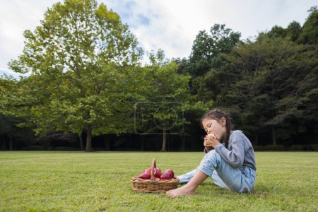 Téléchargez les photos : Fille manger des pommes dans le parc - en image libre de droit