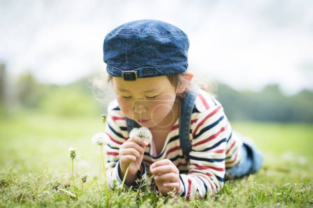 Happy little girl playing with dandelion
