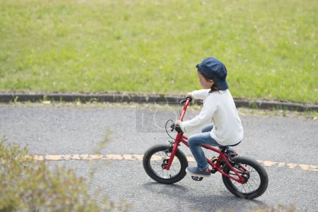 Photo for Happy little girl riding a red bicycle - Royalty Free Image