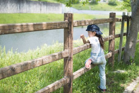 Téléchargez les photos : Petite fille en salopette sur la clôture - en image libre de droit