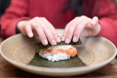 Téléchargez les photos : Un enfant qui fait des sushis roulés à la main - en image libre de droit
