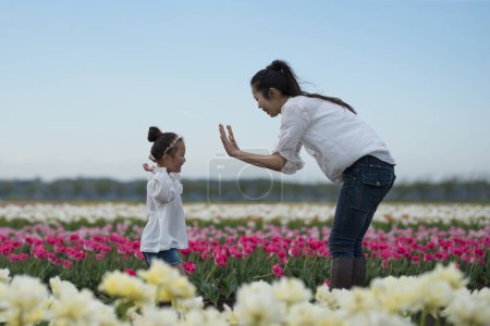 Téléchargez les photos : Bonne petite fille jouant dans un champ de tulipes - en image libre de droit
