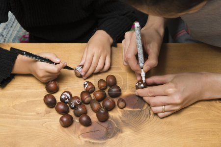 Photo for Mother and daughter drawing a pattern on acorns - Royalty Free Image