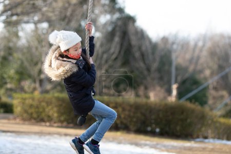 Téléchargez les photos : Fille jouant sur une balançoire dans la cour d'école - en image libre de droit