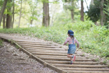 Photo for Little girl climbing the stairs in the forest - Royalty Free Image