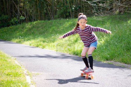 Téléchargez les photos : Fille jouer avec skateboard dans le parc - en image libre de droit