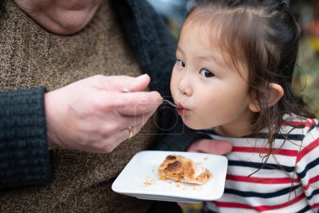 Photo for Little girl eats a delicious sweet pie in the park - Royalty Free Image