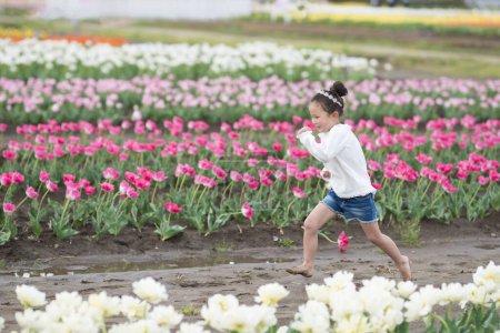Téléchargez les photos : Une fille jouant dans un jardin de fleurs - en image libre de droit