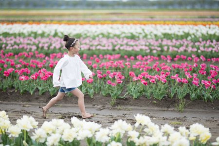Foto de Una chica jugando en un jardín de flores - Imagen libre de derechos