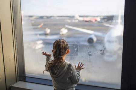 Téléchargez les photos : Petite fille regardant un avion à l'aéroport - en image libre de droit