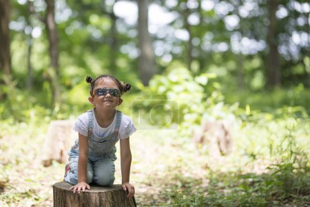 Photo for Little girl wearing sunglasses in forest - Royalty Free Image