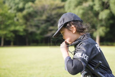 Téléchargez les photos : Petite fille portant un costume de police sifflant - en image libre de droit