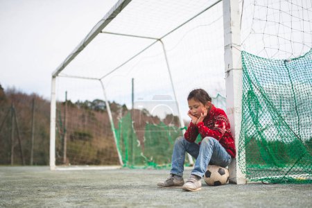 Téléchargez les photos : Fille assise sur un ballon de football - en image libre de droit