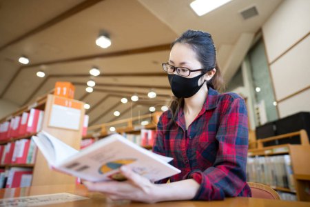 Téléchargez les photos : Femme lisant un livre portant un masque - en image libre de droit