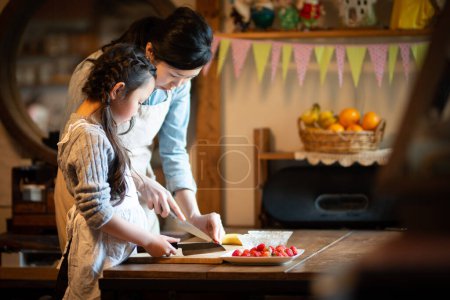 Téléchargez les photos : Jeune mère et fille cuisiner ensemble dans la cuisine - en image libre de droit