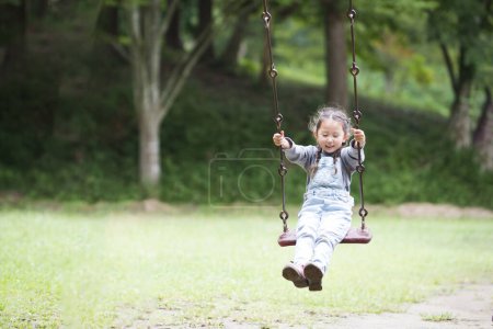 Foto de Asiático chica en swing en el parque - Imagen libre de derechos