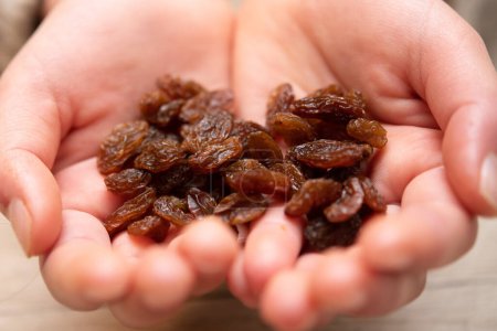Téléchargez les photos : Mains d'un enfant avec beaucoup de raisins secs - en image libre de droit