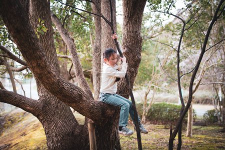 Foto de Niña feliz trepando un árbol - Imagen libre de derechos