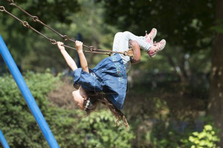 Téléchargez les photos : Asiatique fille jouer sur swing dans l 'parc - en image libre de droit