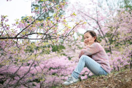 Photo for Young asian girl having fun  in  park with  sakura trees - Royalty Free Image