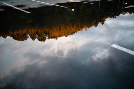 Téléchargez les photos : Paysage reflété dans une flaque d'eau d'un parking - en image libre de droit
