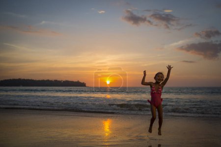 Téléchargez les photos : Jeune fille sautant sur la plage pendant le coucher du soleil d'été. - en image libre de droit