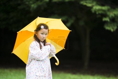Téléchargez les photos : Bonne petite fille marchant avec un parapluie - en image libre de droit