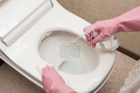 Person cleaning the white toilet 