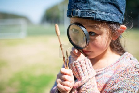 Téléchargez les photos : Jeune fille avec loupe regardant sur la plante - en image libre de droit