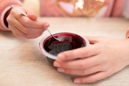 Hands of child eating jelly