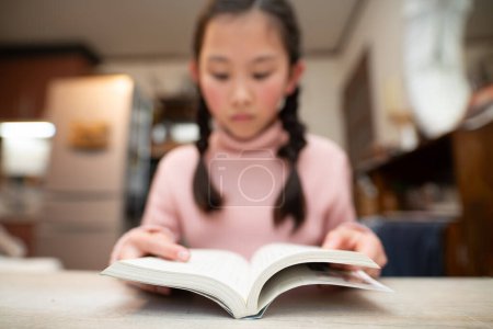 Foto de Asiático chica leyendo libro en biblioteca - Imagen libre de derechos