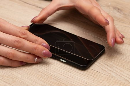 Téléchargez les photos : Mains de femme mettant de la vitre de protection sur smartphone - en image libre de droit