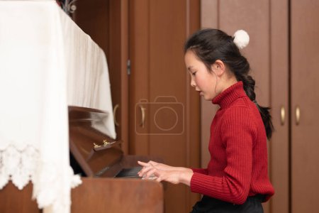 Foto de Joven asiático chica jugando piano en casa - Imagen libre de derechos