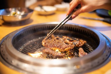 Téléchargez les photos : Mains de femme griller barbecue coréen - en image libre de droit