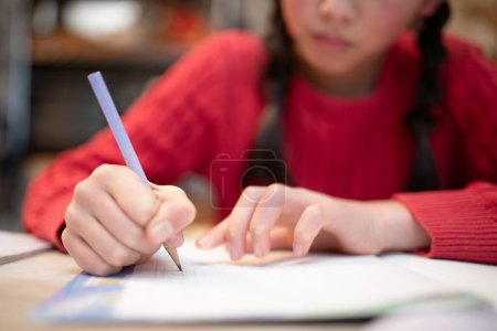Téléchargez les photos : Asiatique fille écriture dans un notebook à la maison. - en image libre de droit