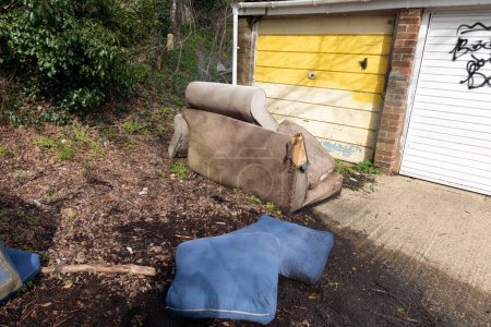 Ein verlassener und umgeworfener Sofa-Sessel in der Garage kippte im Regen um