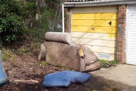 A Abandoned and Dumped Sofa Armchair at the Garages Flytipped in the Rain